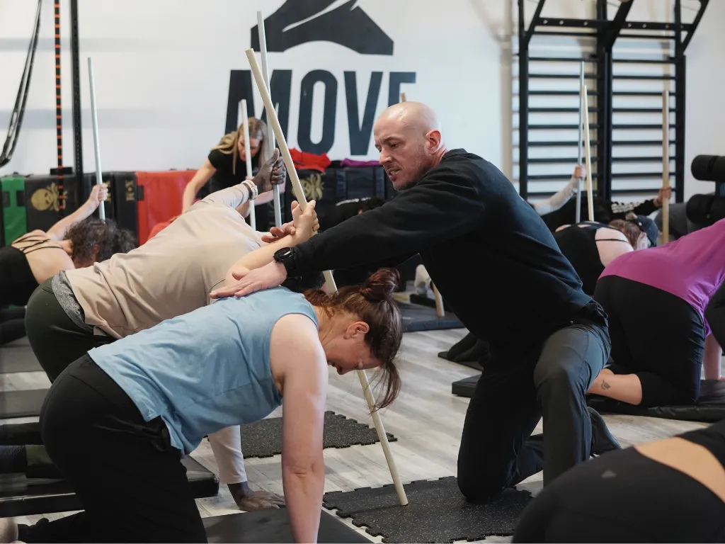 Rebuild program at Move Strong — coach cueing a member through a mobility drill in Kitchener-Waterloo